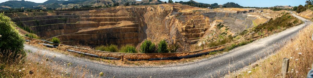 A mining site with terraced excavation areas, a railway track, and a road curving through the landscape.