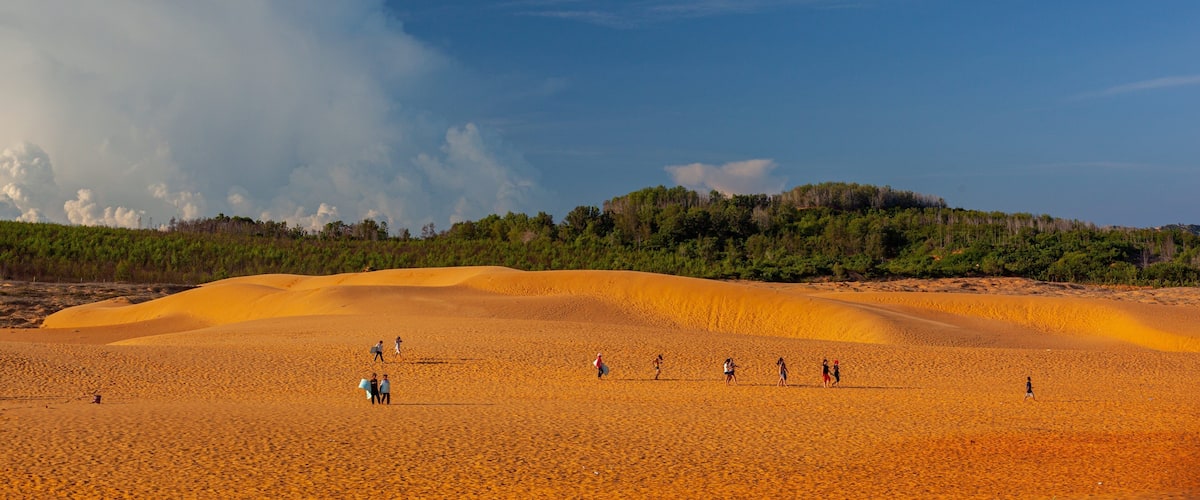 Mui Ne Sand Dunes which includes desert views and a beach as well as a small group of people