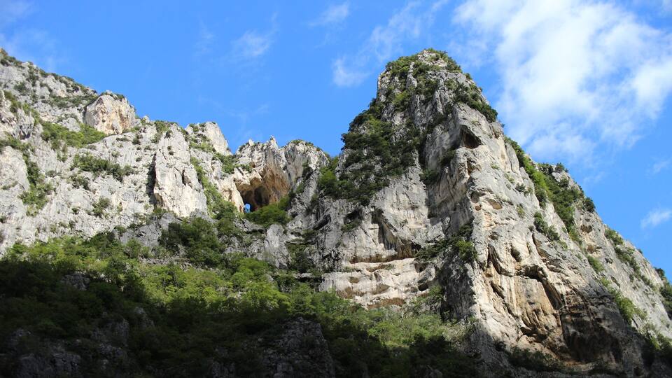 A rugged mountain landscape with rocky cliffs and sparse vegetation.