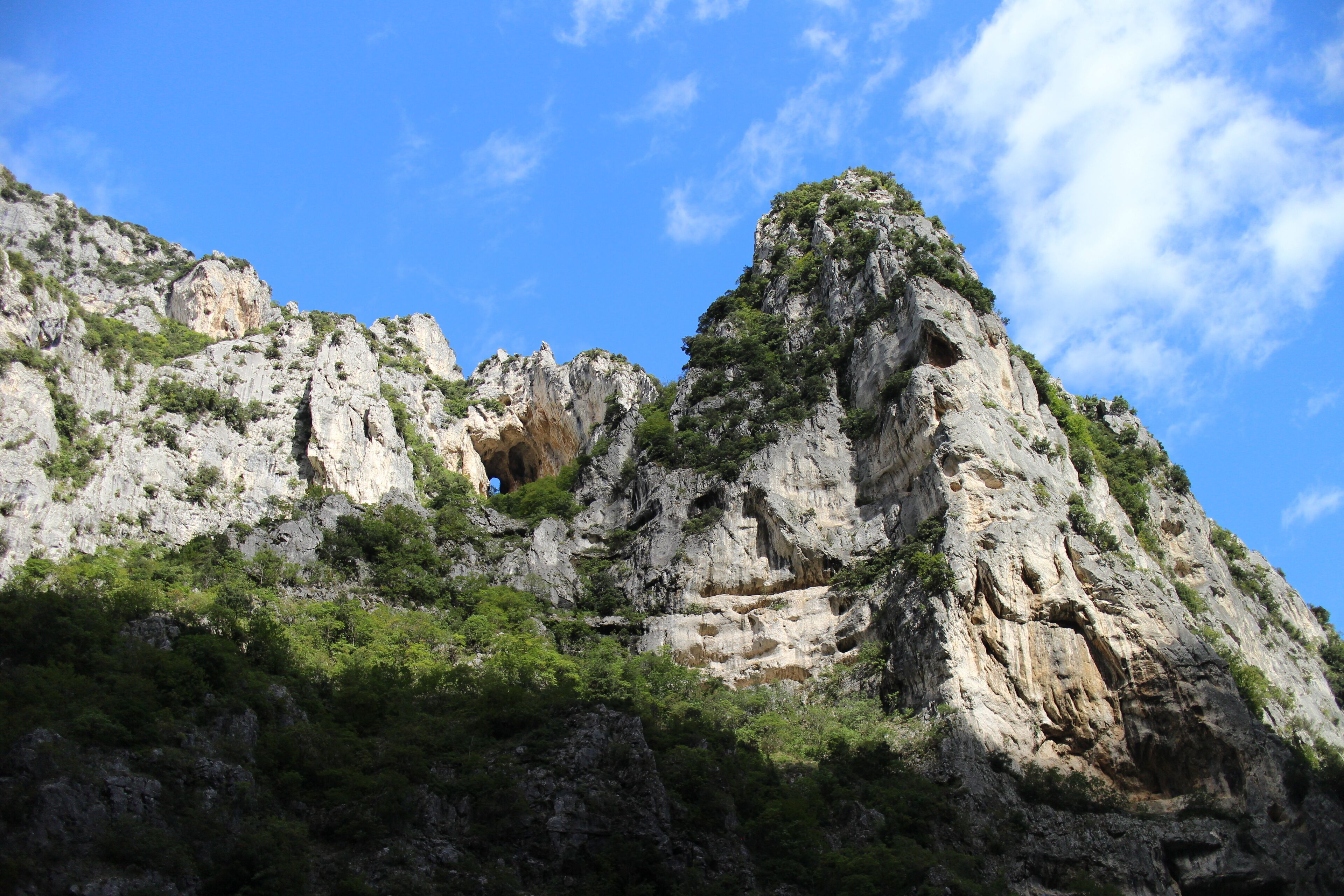 A rugged mountain landscape with rocky cliffs and sparse vegetation.