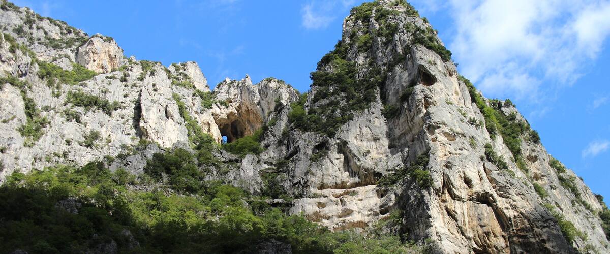 A rugged mountain landscape with rocky cliffs and sparse vegetation.