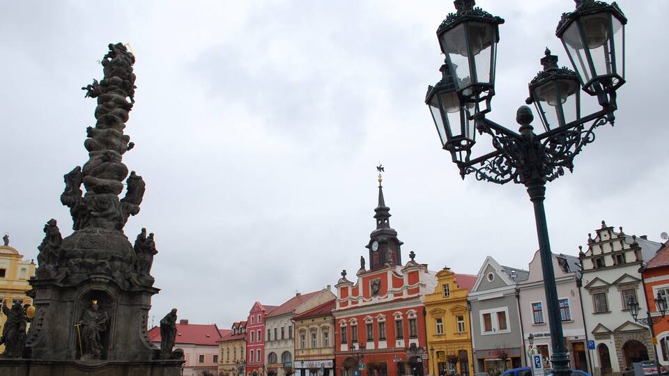 A historic square with colorful buildings, a statue, and a street lamp.