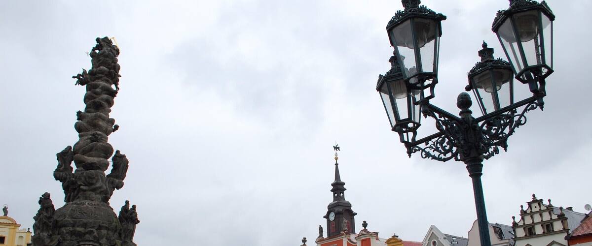 A historic square with colorful buildings, a statue, and a street lamp.