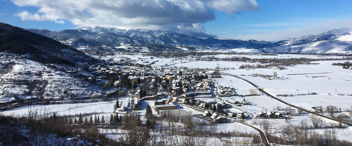 A snow-covered town nestled in a valley with mountains in the background.
