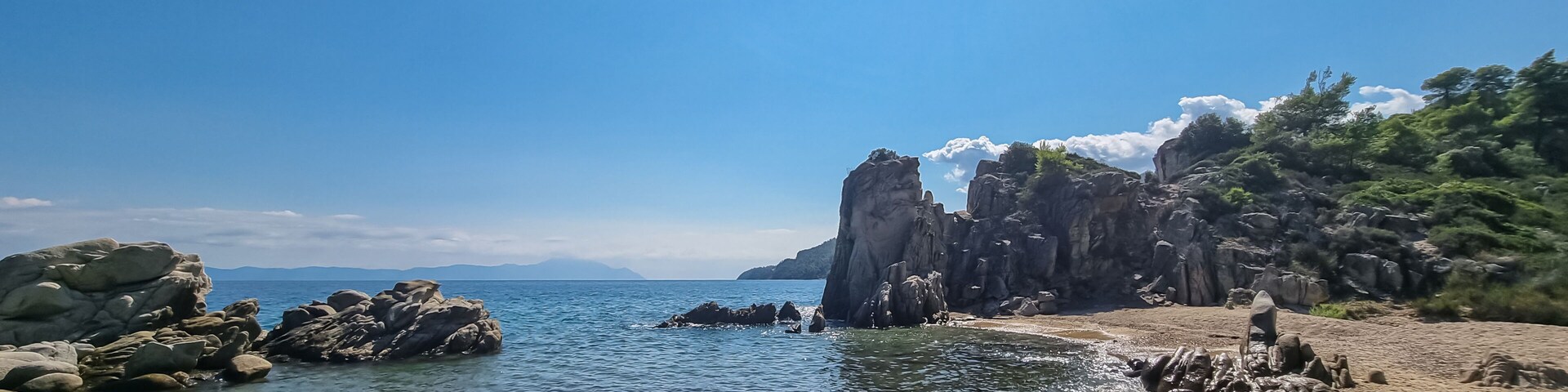 Una costa rocosa con aguas cristalinas y un cielo soleado.