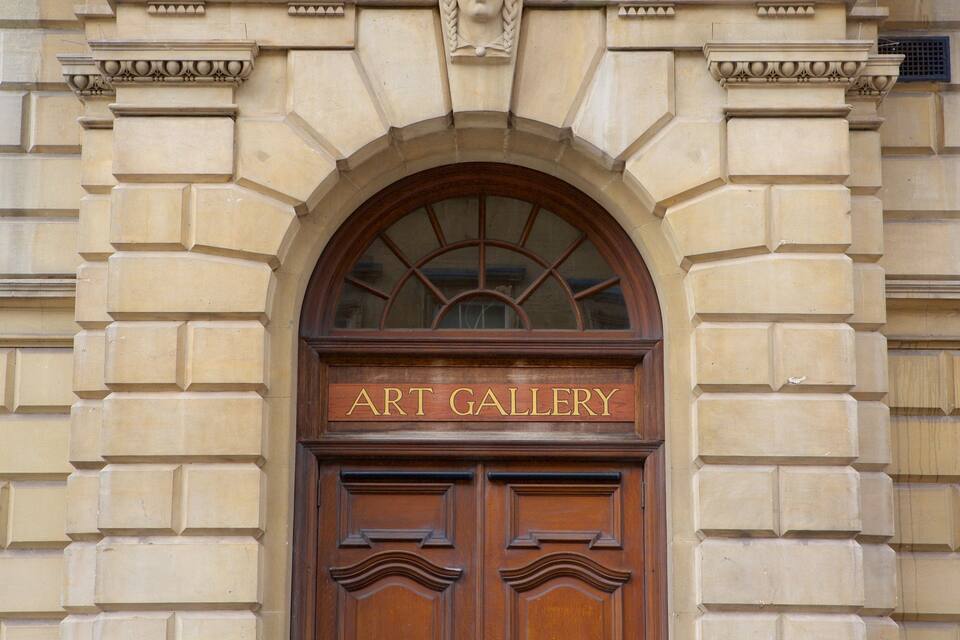 Una porta de fusta amb la inscripció "GALERIA D'ART" escrita al damunt, emmarcada en una estructura de pedra amb arc.