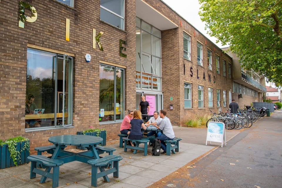 A brick building with outdoor seating and bicycles parked outside.