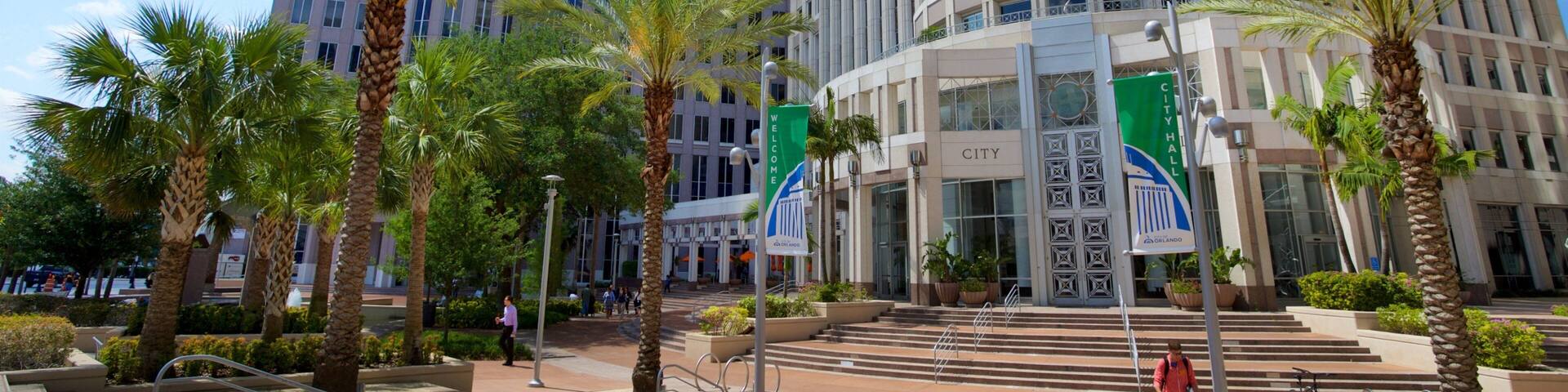 A city hall building with a 'Welcome' sign, palm trees, and a clear blue sky.