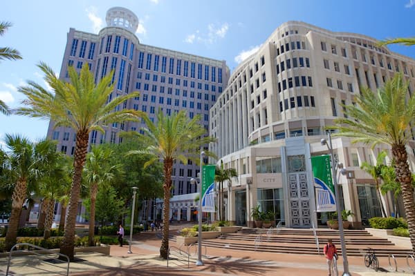 A city hall building with a 'Welcome' sign, palm trees, and a clear blue sky.