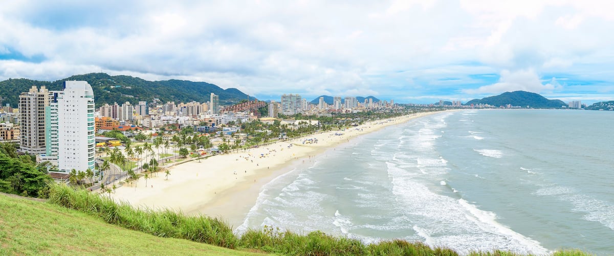 Panoramic aerial view of the Cove Beach at Guaruja SP Brazil. People on the beach, the sand, sea waves and the city on background. Place known as Praia da Enseada. Brazilian coastal city.