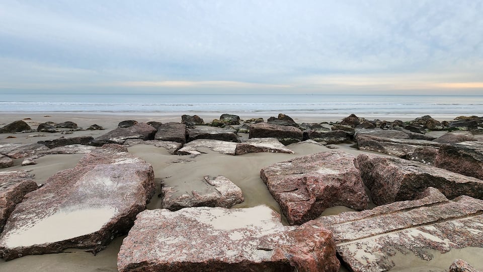 A rocky shoreline with large boulders and a calm sea.