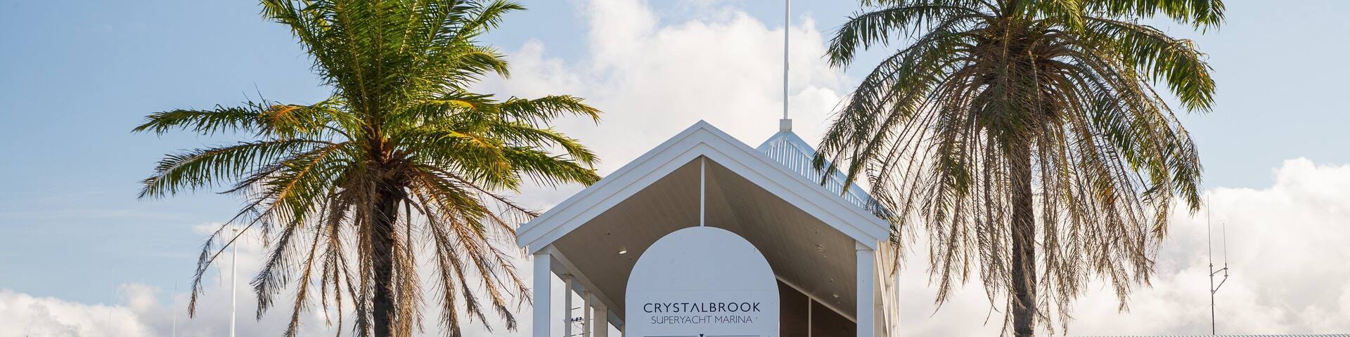 A marina building with a sign reading "Crystalbrook Superyacht Marina Port Douglas".
