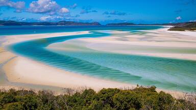 Un paysage côtier caractérisé par des eaux turquoise limpides, des plages de sable blanc et une végétation verdoyante.