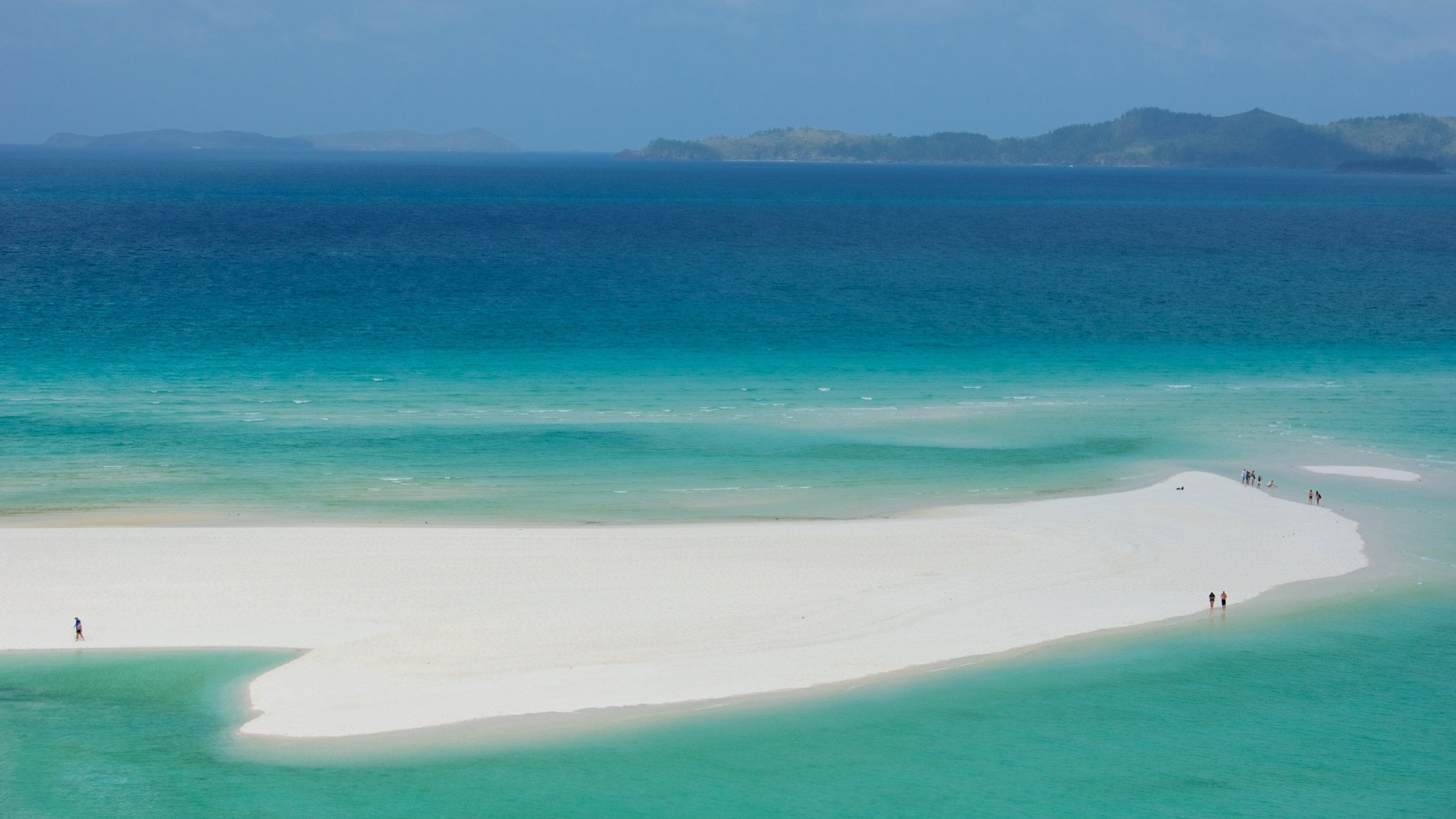 A beach with clear turquoise waters and white sand.