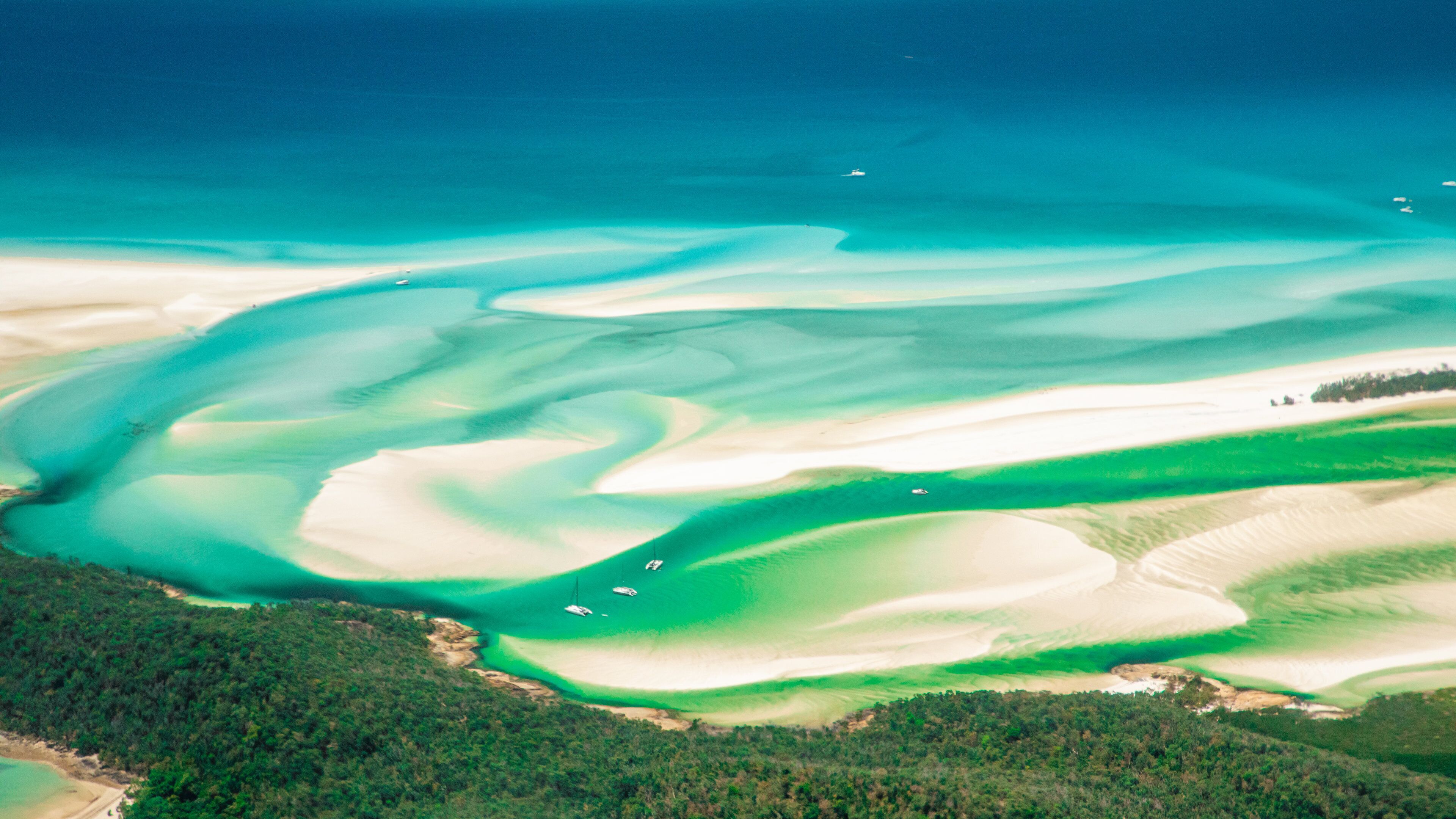 A coastal landscape with clear turquoise waters, sandy beaches, and dense green forest.