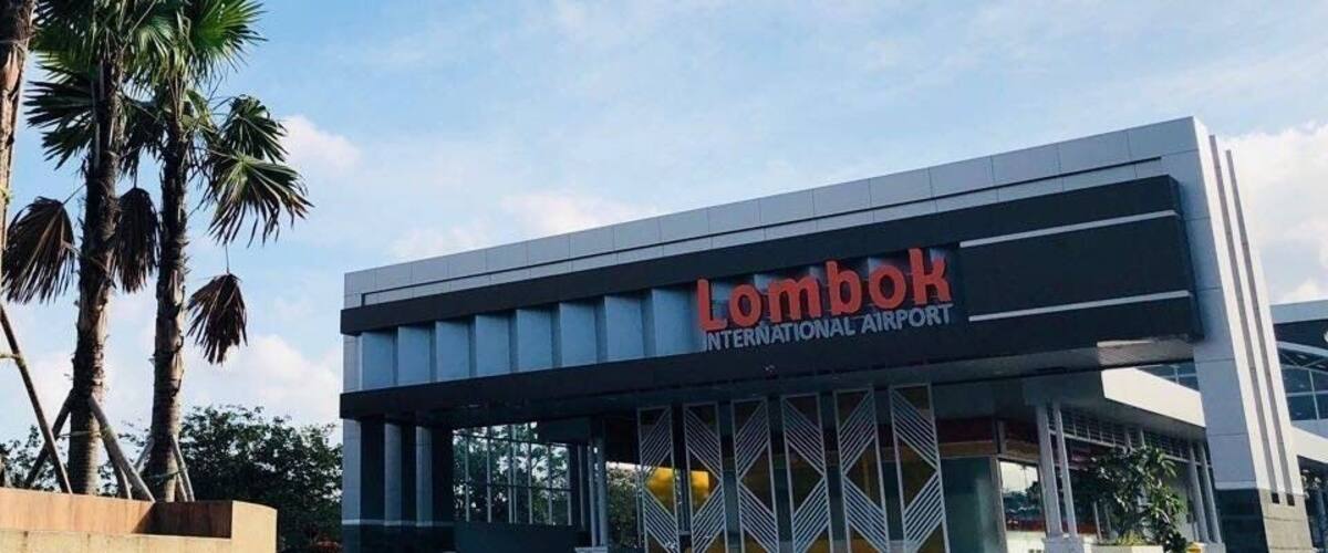 The exterior of Lombok International Airport with palm trees and a clear sky.