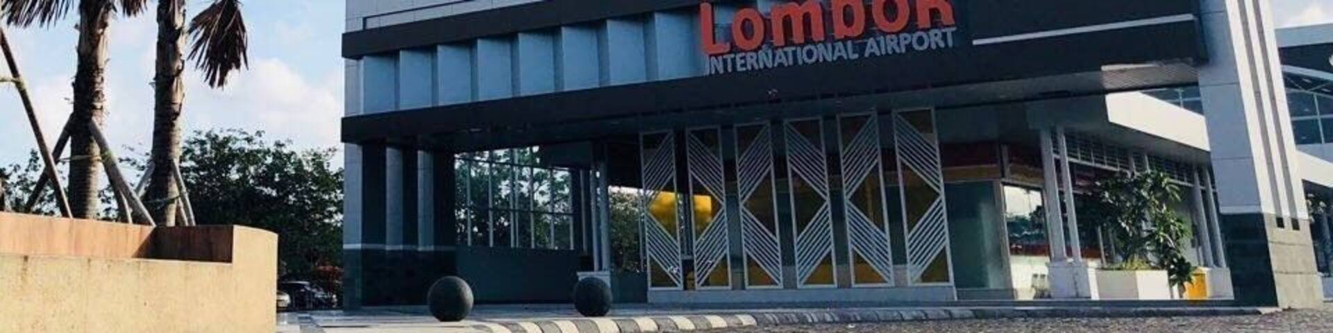 The exterior of Lombok International Airport with palm trees and a clear sky.