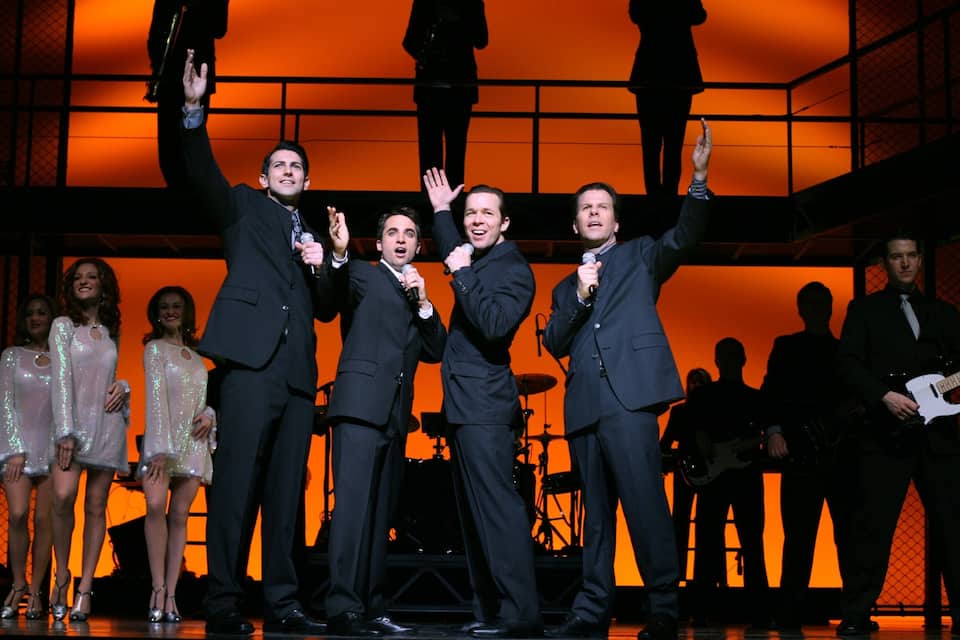 A group of people on a stage with a bright orange background.