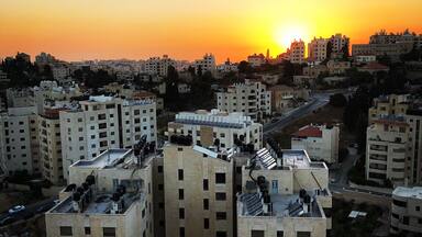 A cityscape at sunset with multiple high-rise buildings and a clear sky.
