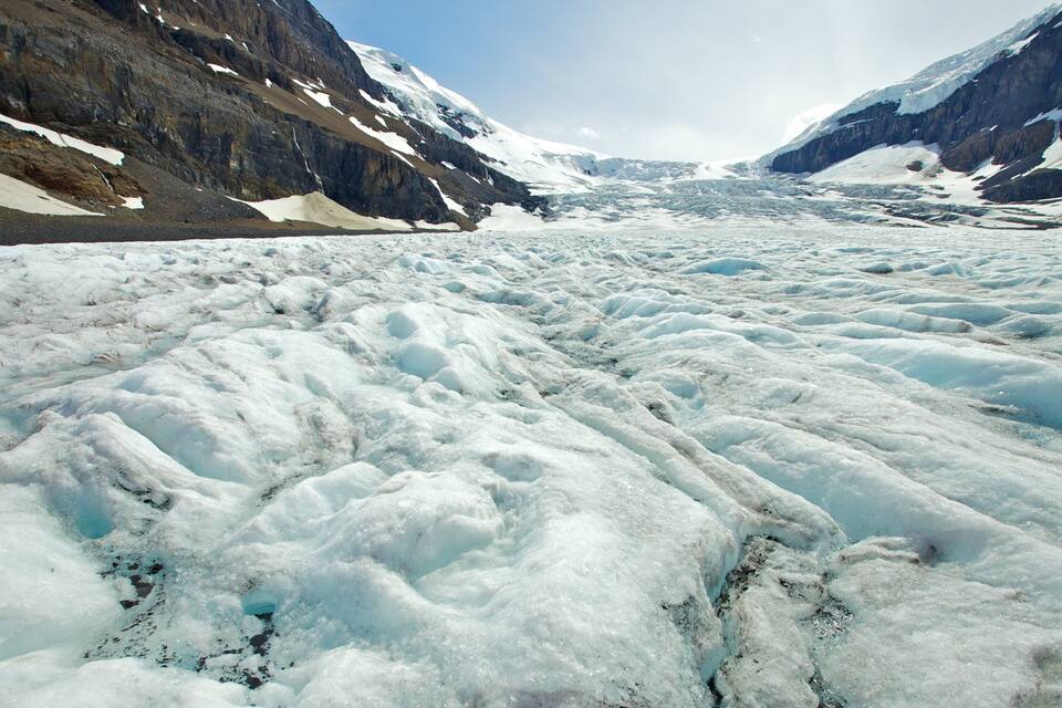 A glacier with rugged mountain sides.