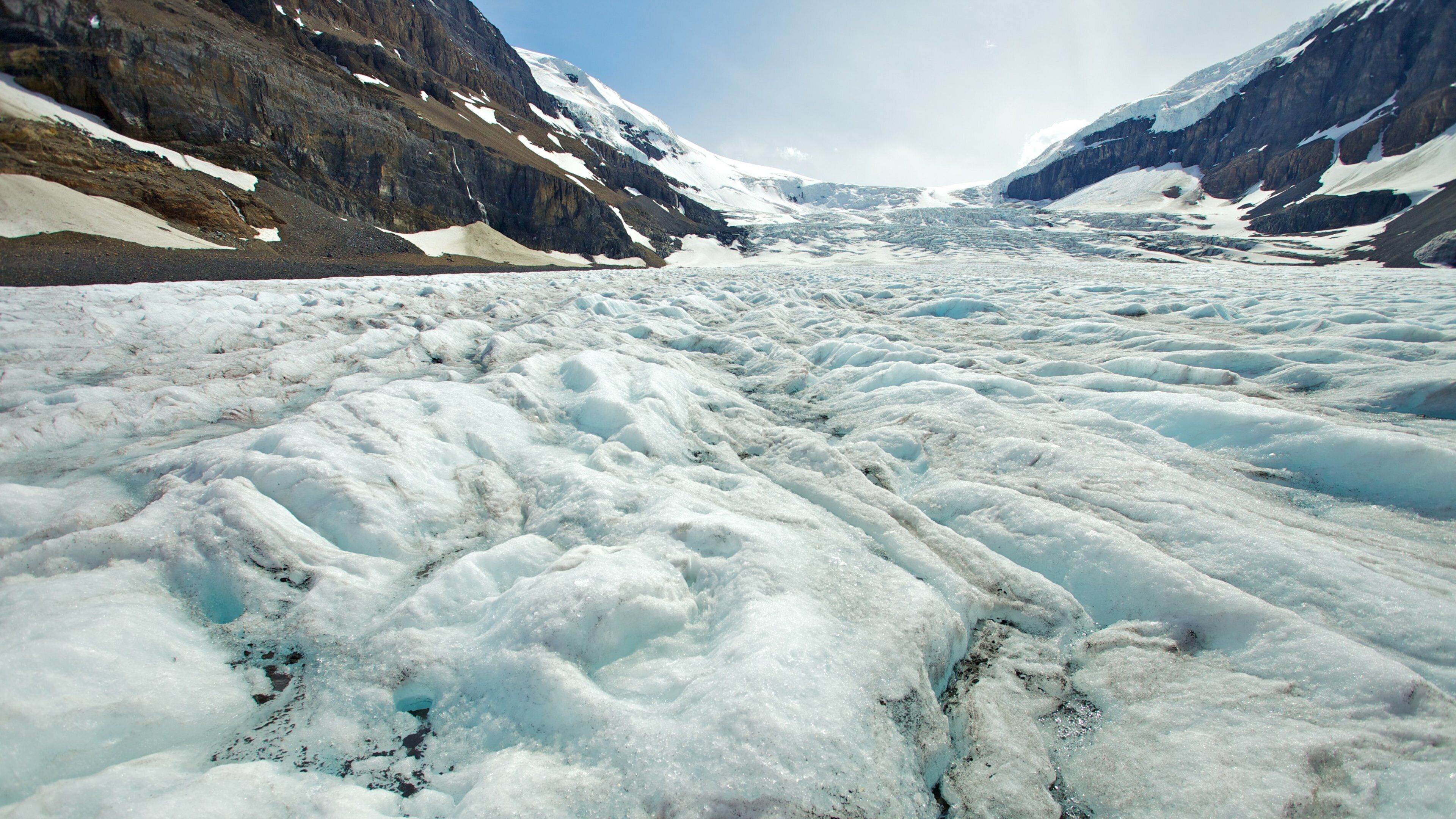 A glacier with rugged mountain sides.