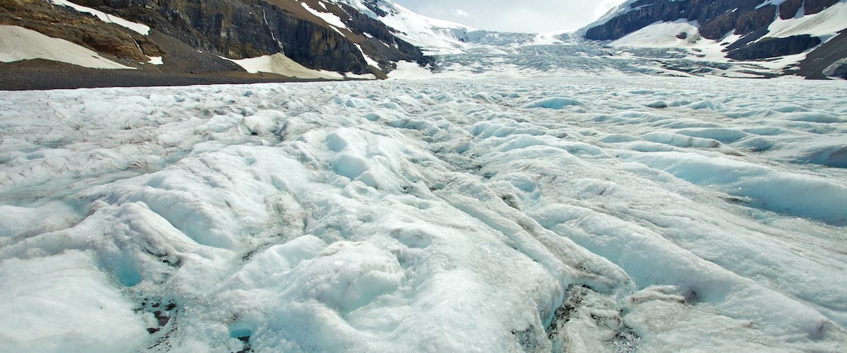 A glacier with rugged mountain sides.