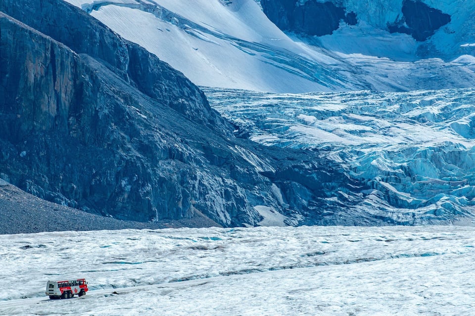 A glacier with a red vehicle on the ice.
