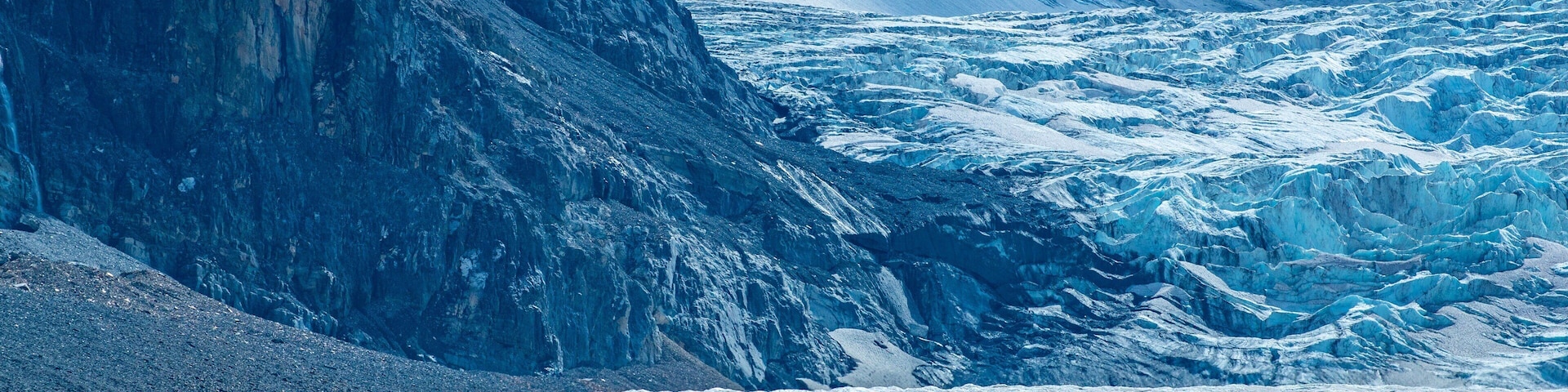 Un glaciar con un vehículo rojo sobre el hielo.