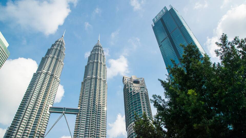 The Petronas Towers and a modern skyscraper in Kuala Lumpur.