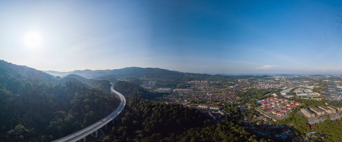 A highway curving through a mountainous landscape with a city in the valley below.