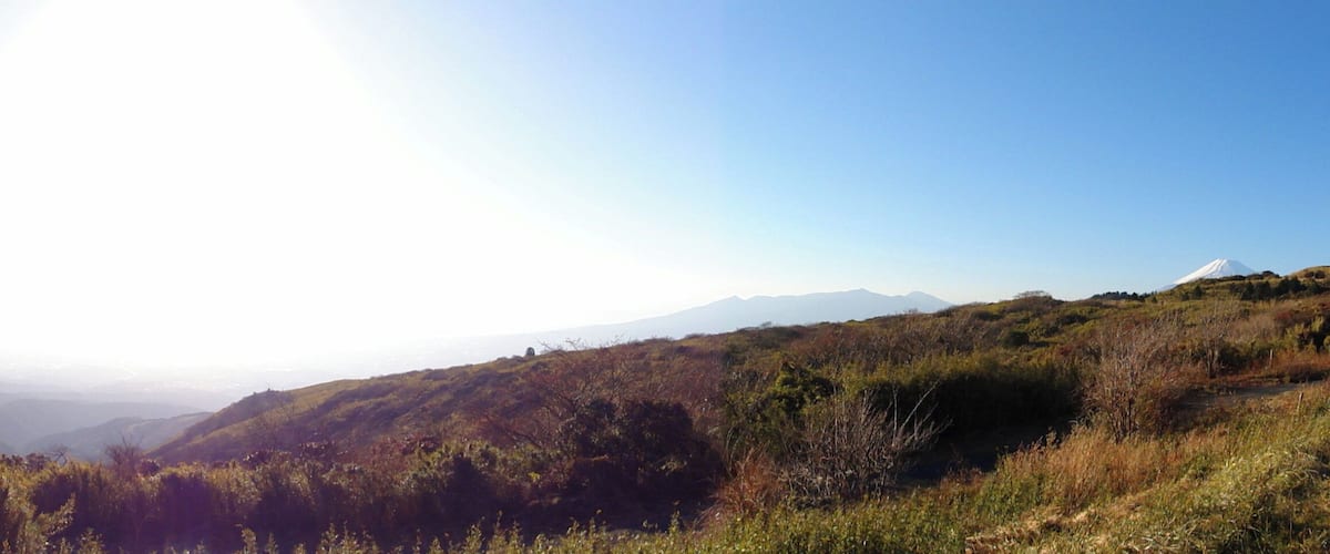 A valley with a mountain range in the distance and a clear sky.