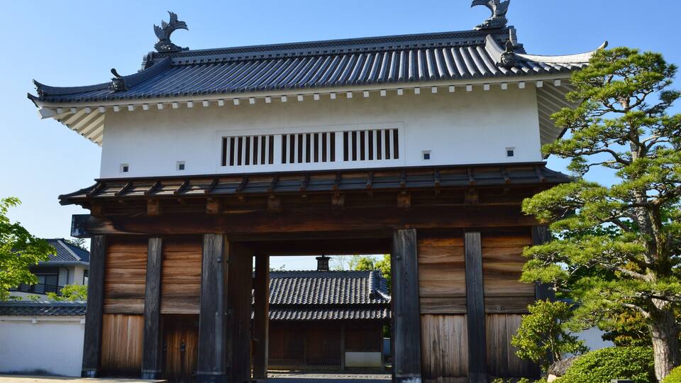 A traditional Japanese building with a tiled roof, wooden pillars, and a stone pathway.