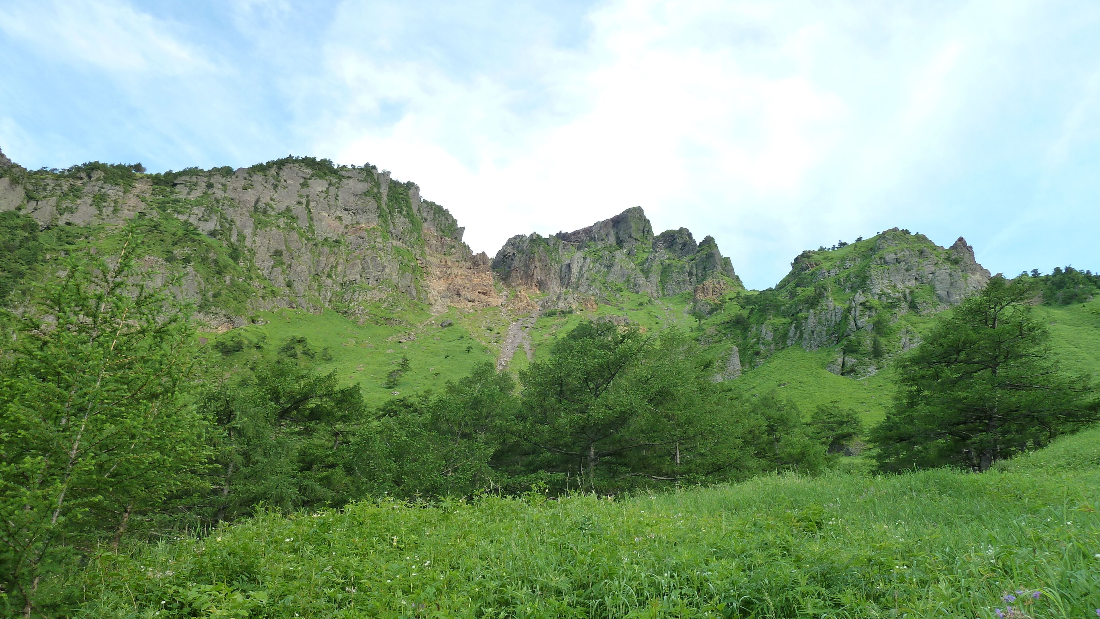 A mountainous landscape with green vegetation and rocky cliffs.