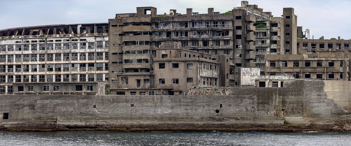 A large, multi-story, dilapidated building with visible structural damage and broken windows.