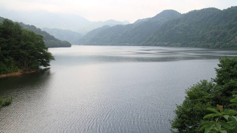 A calm lake surrounded by lush green hills.
