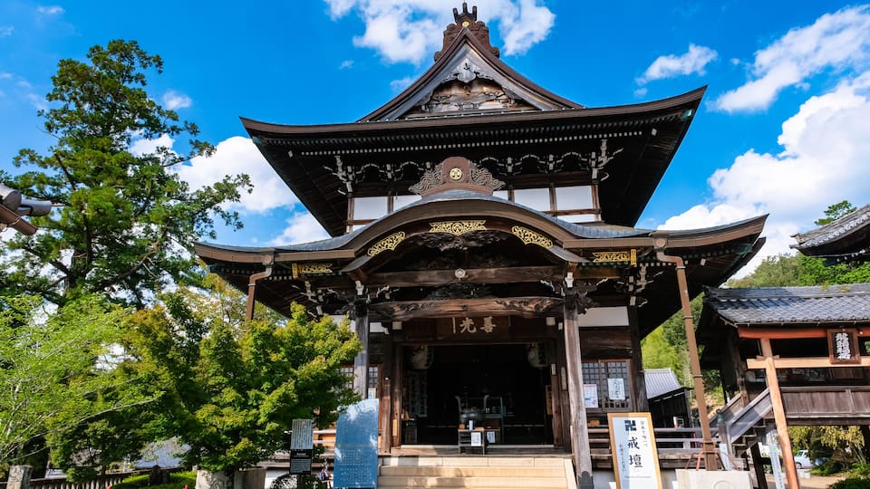 A traditional Japanese gate with ornate wooden architecture and a clear blue sky in the background.