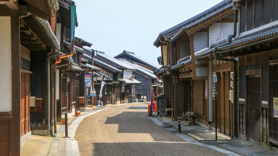 A traditional Japanese street with wooden buildings and a gravel road.