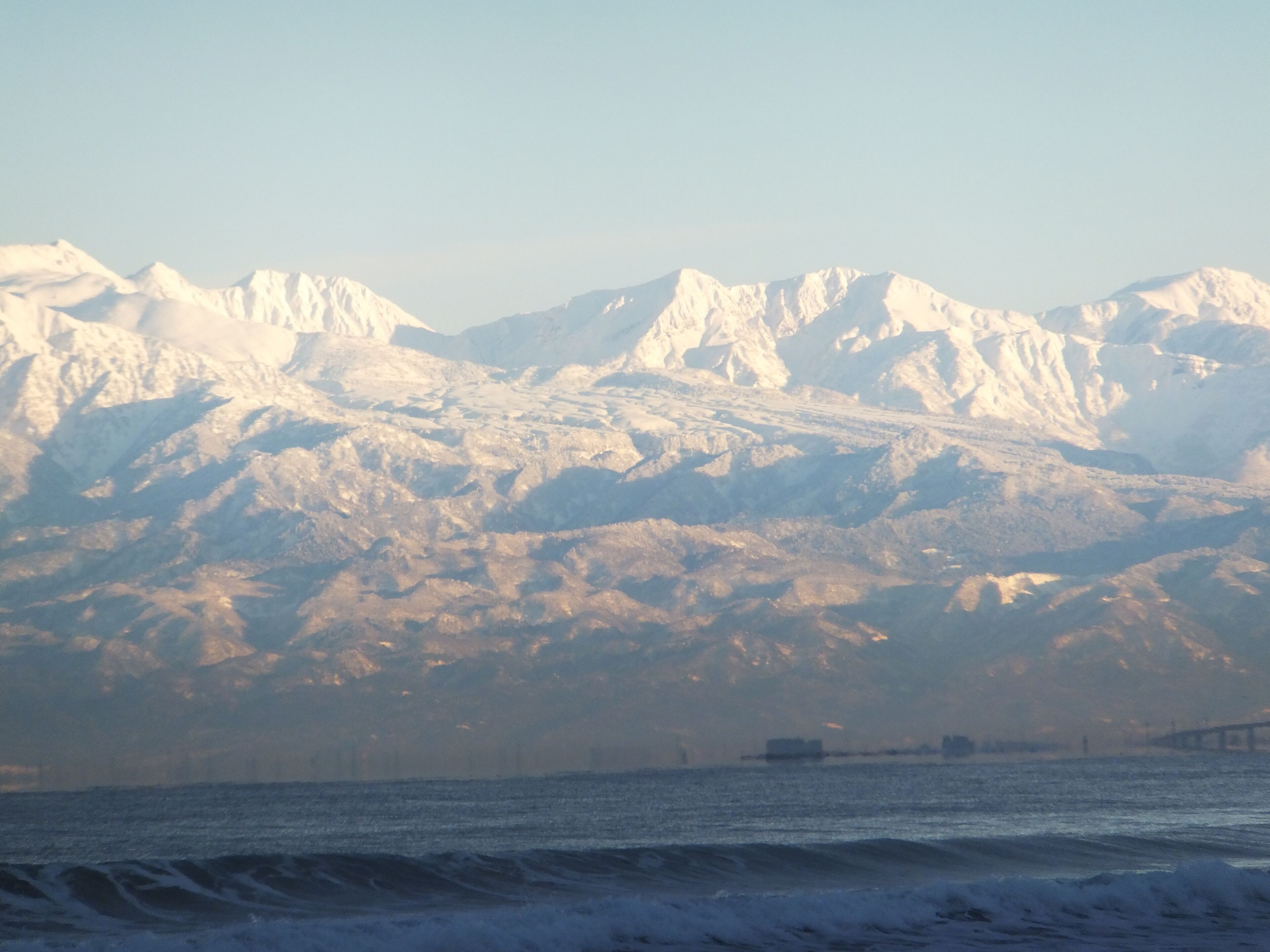 A snow-covered mountain range with a bridge in the foreground.