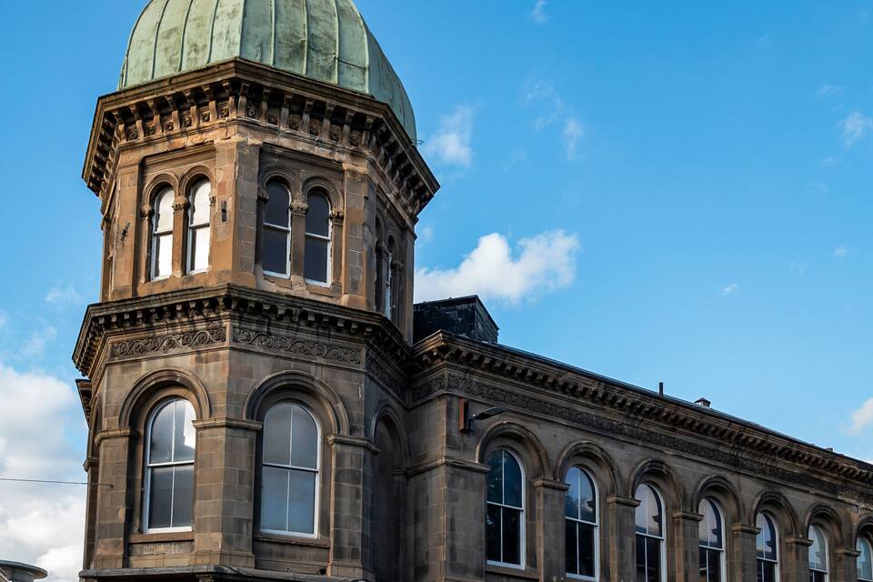 A historic building with a green dome and a clock tower.