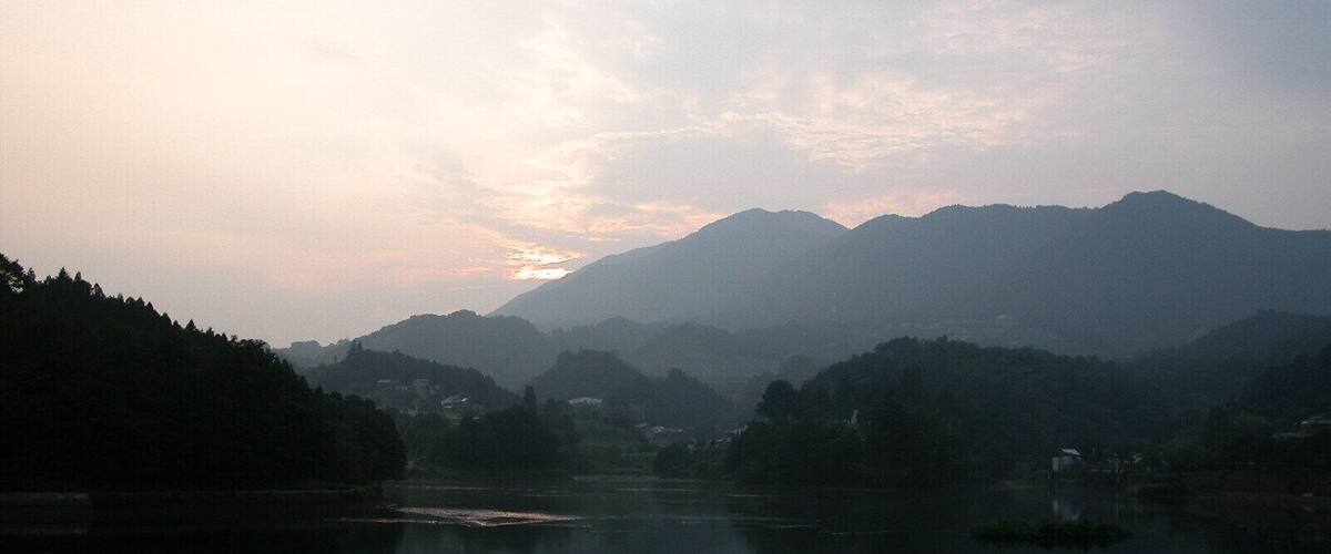A calm lake with mountains in the background and a clear sky.