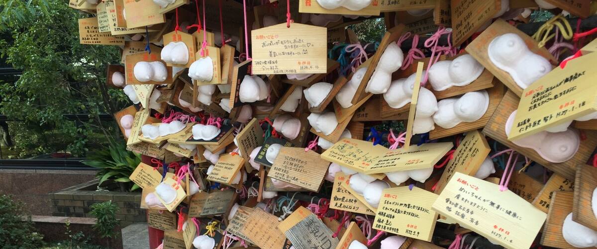 A collection of white paper bags with handwritten notes attached, displayed on a wooden structure outdoors.