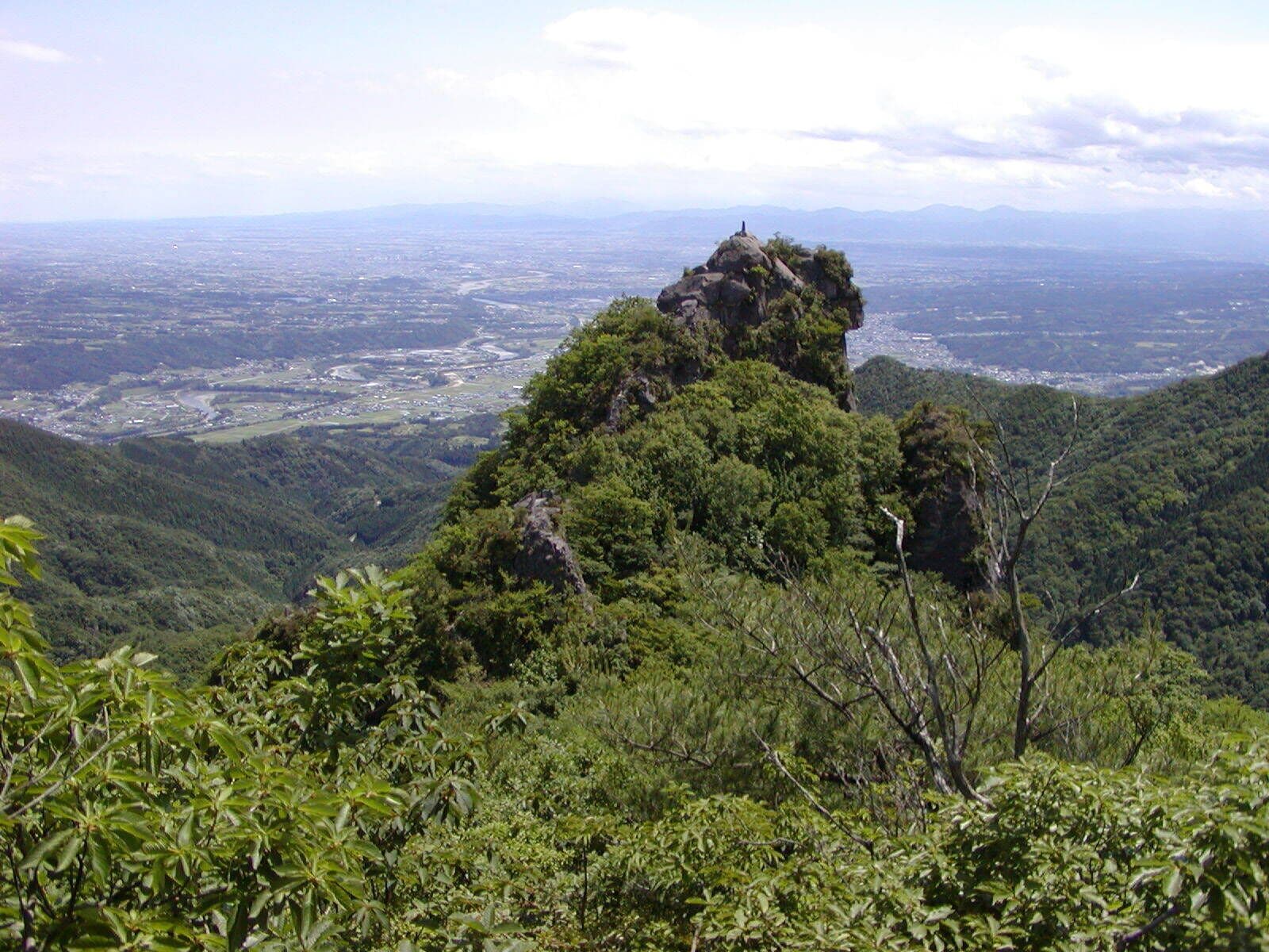A mountainous landscape with dense green vegetation and a prominent rocky peak.