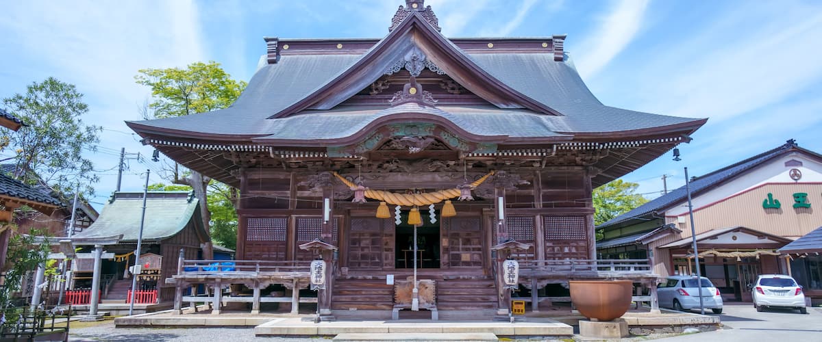 A traditional Japanese temple with a curved roof, wooden structure, and a large stone lantern in front.