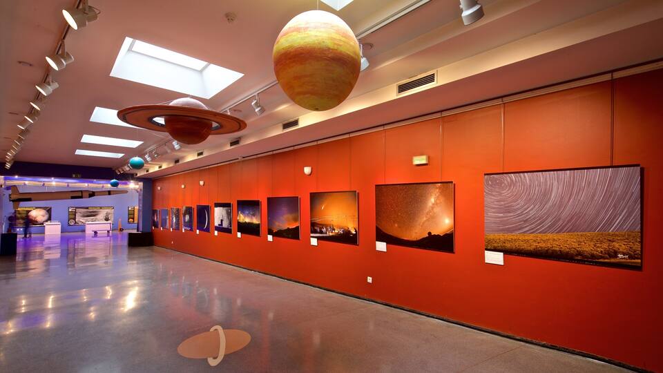 A museum corridor with a series of planetary models and starry night sky images on the wall.