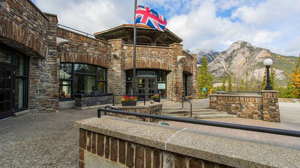 A stone building with a flag, a sign reading "Entrance Tree", and mountains in the background.