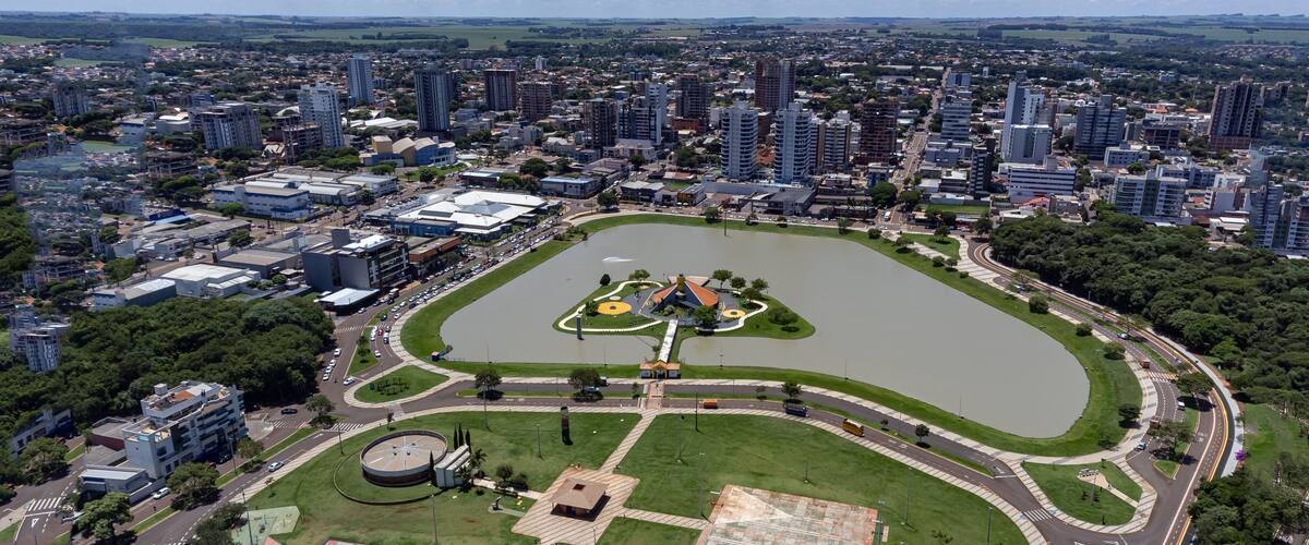 An aerial view of a city with a large central park, a lake, and surrounding high-rise buildings.