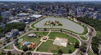 An aerial view of a city with a large central park, a lake, and surrounding high-rise buildings.