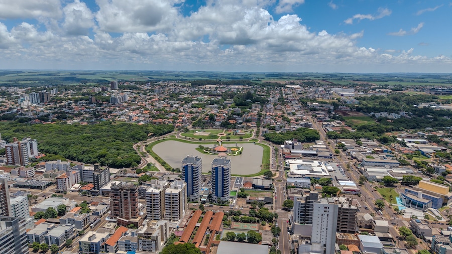 Un paisaje urbano con un parque grande, varios edificios altos y una vista distante del campo.