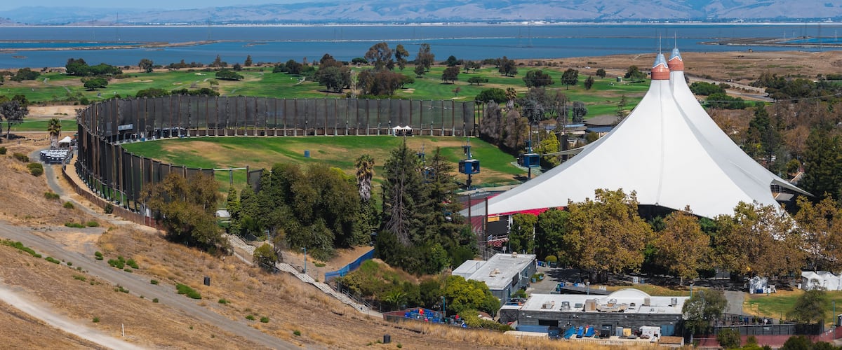 Un parcours de golf doté d’un grand stade et d’une structure distinctive en forme de tente blanche.