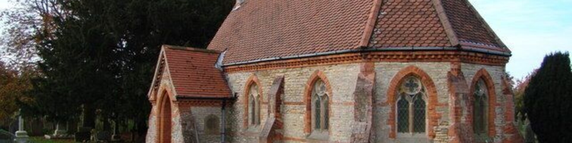 Una iglesia con tejado de tejas rojas y ventanas arqueadas.